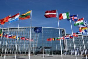 NATO headquarters with flags representing alliance members during defence policy discussions
