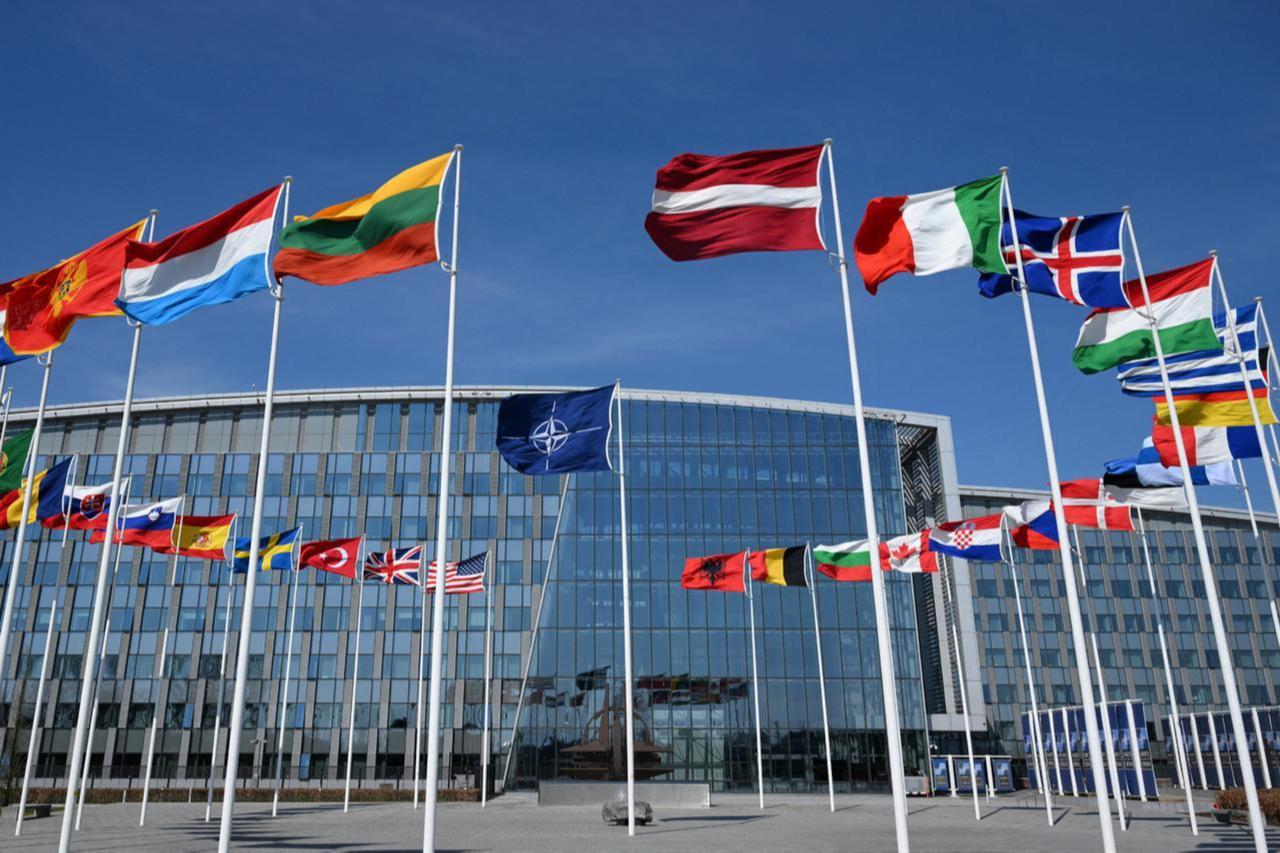 NATO headquarters with flags representing alliance members during defence policy discussions